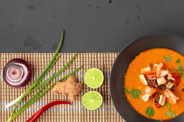 Tom yam Thai çorbası, gri arka planda servis edilir.