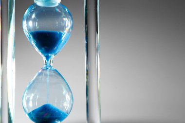 Gri arkaplanda mavi kum saati. Yakın plan.