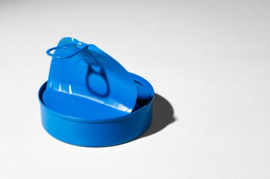 Boyanmış mavi, beyaz zemin üzerinde yüzük bulunan teneke kutu.