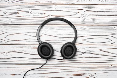 Tahta arka planda kablo olan siyah kulaklıklar.