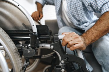 Siyah engelli adam evde tekerlekli sandalyeye oturur.