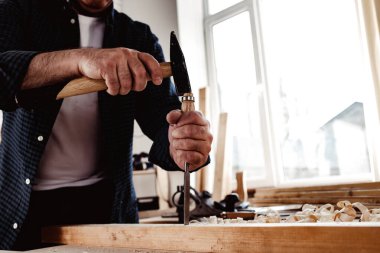 Bir marangozun elleri keski ve çekiçle çalışır.