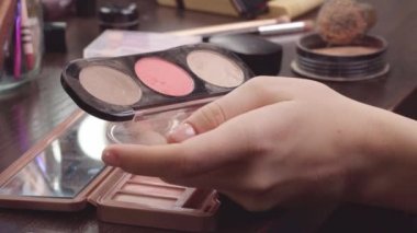 Makyaj yapan kadın elleri yüz makyajından allık sürüyor.