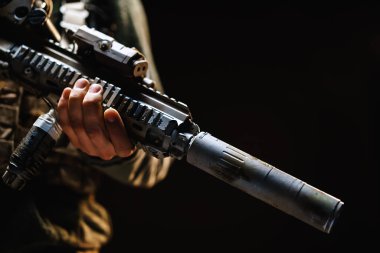 Tanımlanamayan özel kuvvetler askeri siyah arka planda tüfekle dikiliyor.