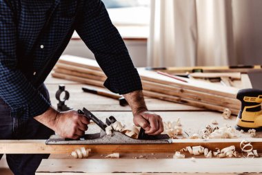 Marangozların elleri el uçağıyla bir tahta döşeme yapıyor.