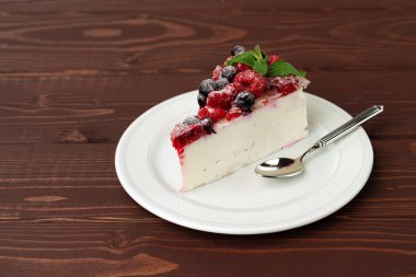 Kahverengi ahşap masada servis edilen çilekli cheesecake.