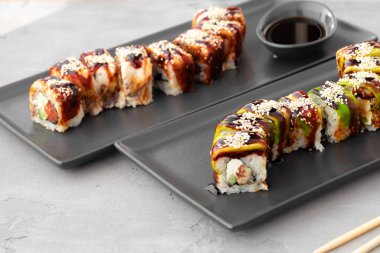 Ejderha suşisi, gri masada yılan balığı ve avokado ile yuvarlanır.