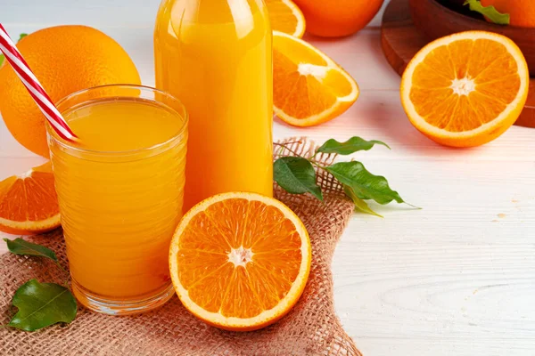 Bottle of orange juice and fresh oranges on table — Stock Photo, Image