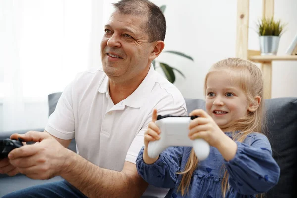 Grootvader en kleindochter spelen thuis videospelletjes. — Stockfoto