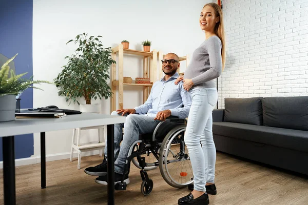 車椅子に座っている障害者の夫の手を握っている妊婦 — ストック写真