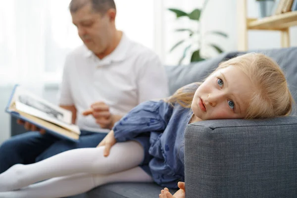 Grootvader leest een boek voor aan zijn kleine graddaughter in de woonkamer — Stockfoto
