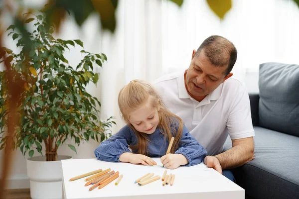Grootvader en kleindochter tekenen samen in de woonkamer — Stockfoto