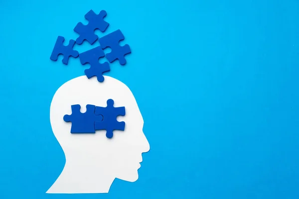 Papiergeschnittener Kopf mit Puzzleteilen auf blauem Hintergrund — Stockfoto