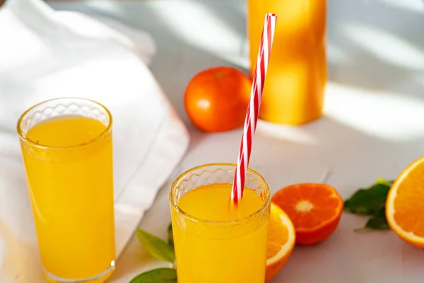 Vaso de jugo de naranja con paja roja en la mesa — Foto de Stock