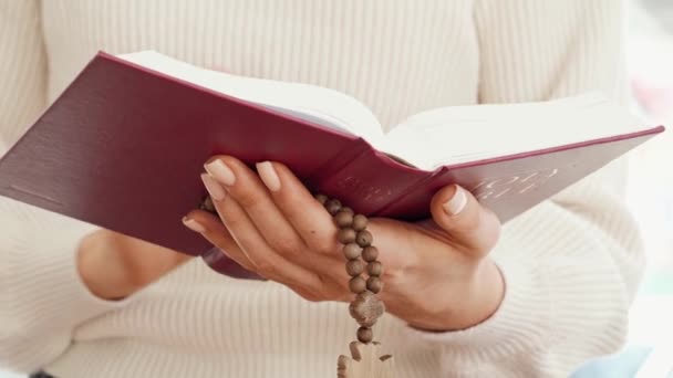 Primo piano di una donna che tiene il libro della Bibbia e perline di legno — Video Stock