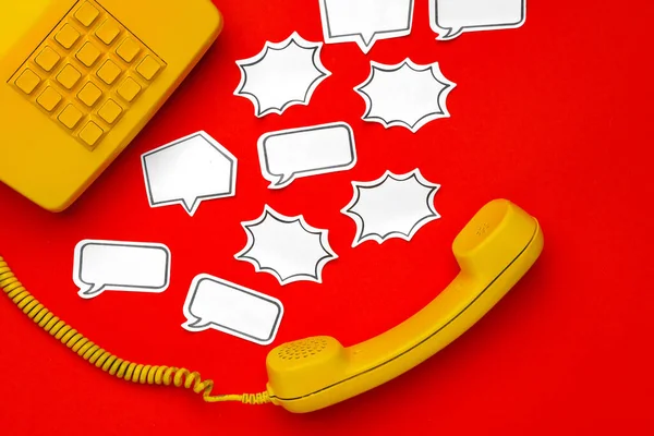 Alto-falante telefone amarelo e bolha de fala no fundo vermelho — Fotografia de Stock