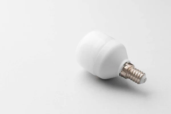 Glödlampa på ljusgrå papper bakgrund — Stockfoto