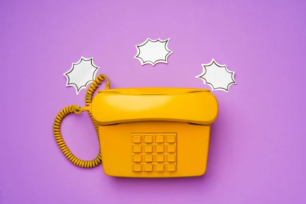 Telefone fixo amarelo com bolha de fala no fundo roxo — Fotografia de Stock