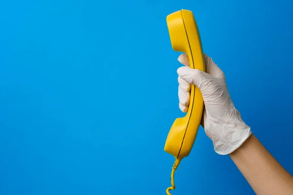 Kobieta w rękawicy medycznej trzymając żółty głośnik telefoniczny — Zdjęcie stockowe