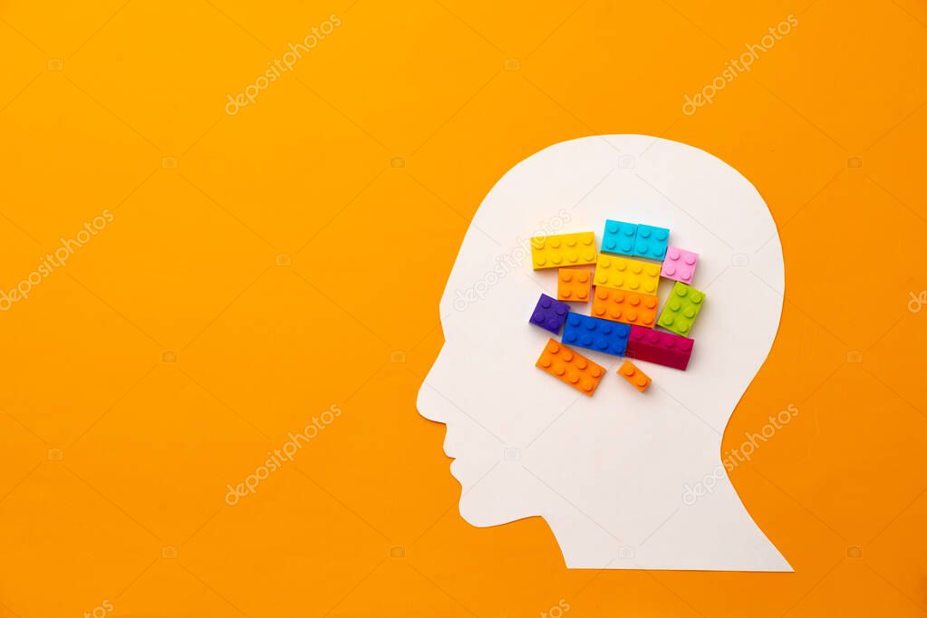 Papercut head silhouette with toy constructor pieces on yellow background