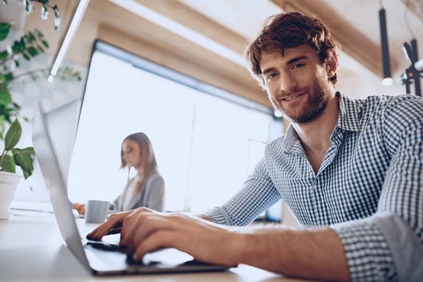 Ung skäggig framgångsrik affärsman som arbetar på laptop i ämbetet med kvinnlig kollega — Stockfoto