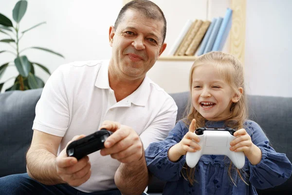 Avô e neta jogando videogames em casa. — Fotografia de Stock