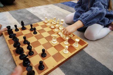 Oturma odasında yerde satranç oynayan küçük kız.