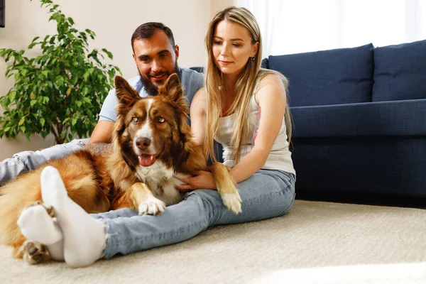Joven pareja amante relajarse en la sala de estar con su mascota perro — Foto de Stock