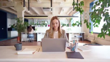 Genç ve güzel iş kadını resmi giysiler giyip ofiste dizüstü bilgisayarla çalışırken erkek arkadaşı belgelerini getiriyor.