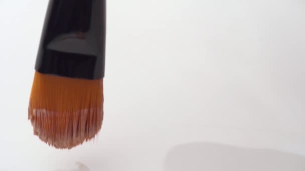 Mancha de fundação facial feita com um pincel na paleta de maquiagem branca de perto — Vídeo de Stock