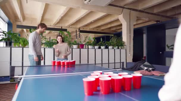 Группа молодых людей играет в пив-понг в большой комнате — стоковое видео