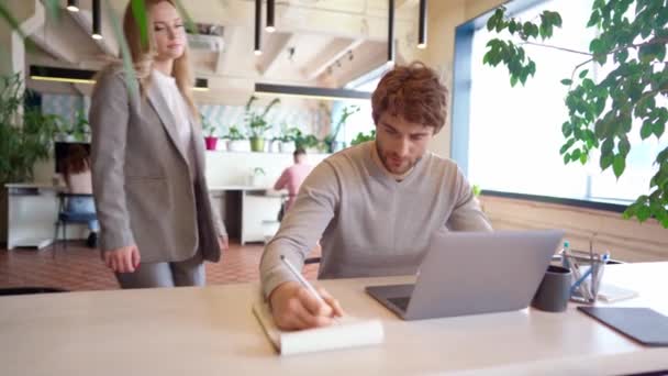 Ung kvinna verkställande lovordar hennes manliga underordnade arbetar på laptop i ämbetet — Stockvideo