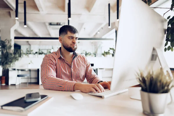 Junger Mann im lässigen Hemd arbeitet im Büro am Computer — Stockfoto