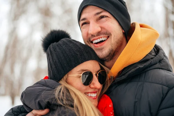 Happy couple hugging and smiling outdoors in snowy park — Stock Photo, Image