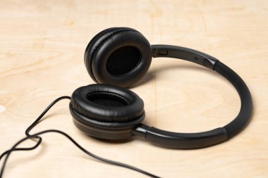 Tahta arka planda kablo olan siyah kulaklıklar.