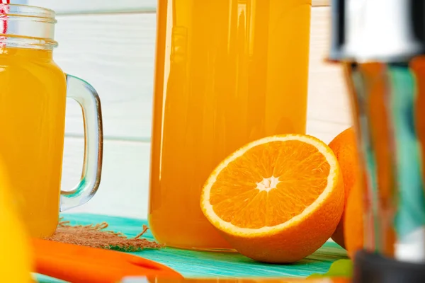 Glass of orange juice and cut oranges on table — Stock Photo, Image