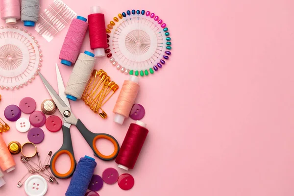 Sewing accessories including thread spools and pins on pink background — Stock Photo, Image