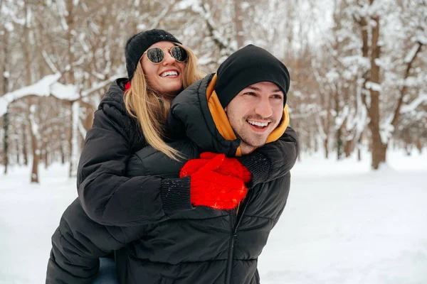 Happy couple hugging and smiling outdoors in snowy park — Stock Photo, Image