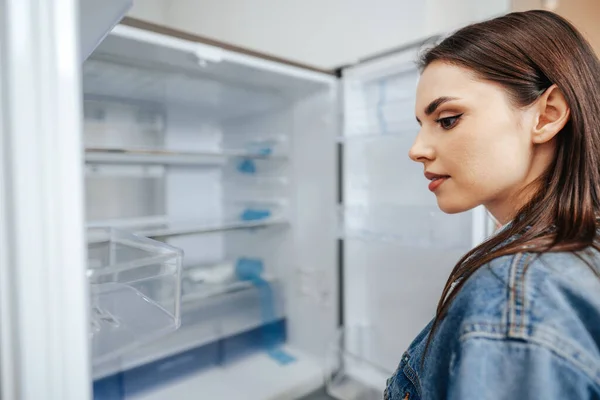 Jovem mulher atraente escolhendo geladeira no hipermercado — Fotografia de Stock