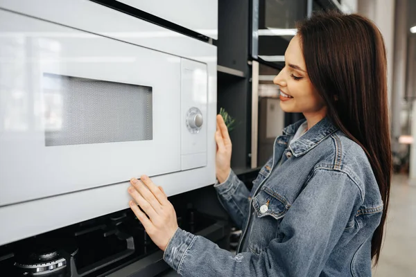 Mujer joven seleccionó un nuevo horno de microondas en el hipermercado — Foto de Stock