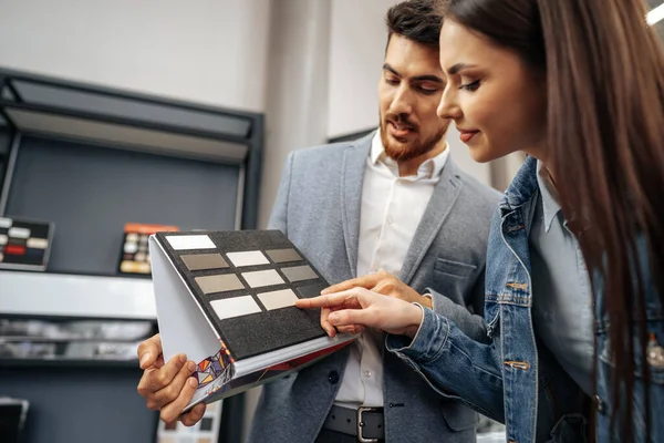 Försäljaren visar färg swatches till dam kund för nya köksmöbler — Stockfoto