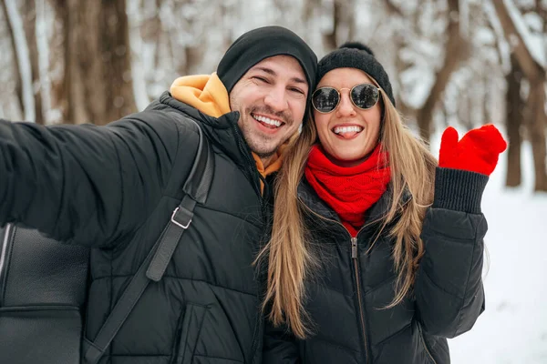 Happy couple hugging and smiling outdoors in snowy park — Stock Photo, Image