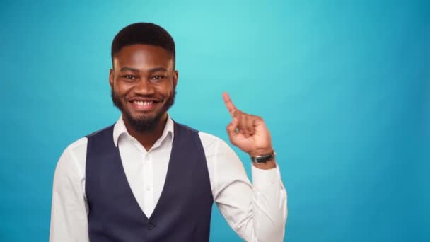 Hombre afroamericano apuntando hacia arriba para copiar el espacio para el anuncio, fondo azul — Vídeos de Stock