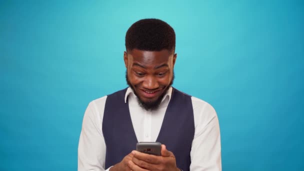 Ung afrikansk amerikansk mand holder smartphone fejrer sejr – Stock-video
