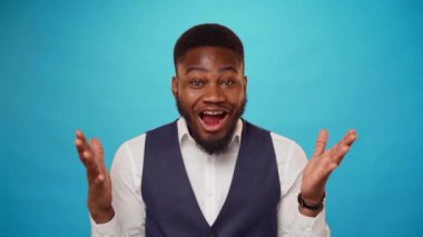 Stüdyoda mavi arkaplanı olan Afrikalı genç adam şaşırdı.