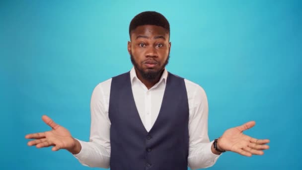 Здивований молодий африканський чоловік на синьому фоні в студії — стокове відео