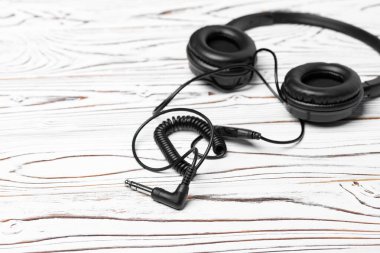 Tahta arka planda kablo olan siyah kulaklıklar.