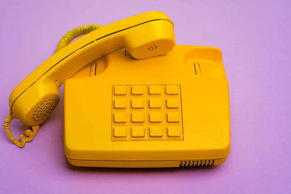 Telefono fisso giallo su sfondo viola da vicino — Foto Stock