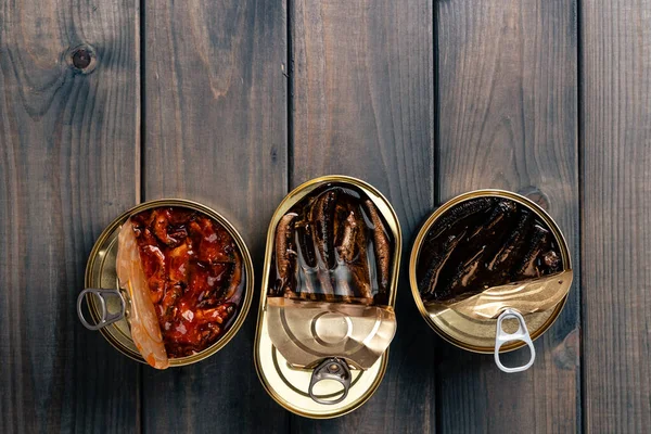 Vista superior de latas abiertas con peces conserva sobre fondo de madera — Foto de Stock