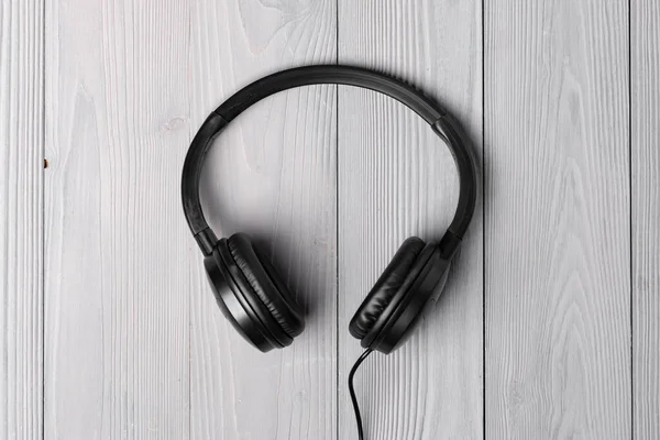 Black headphones with wire on wooden background — Stock Photo, Image